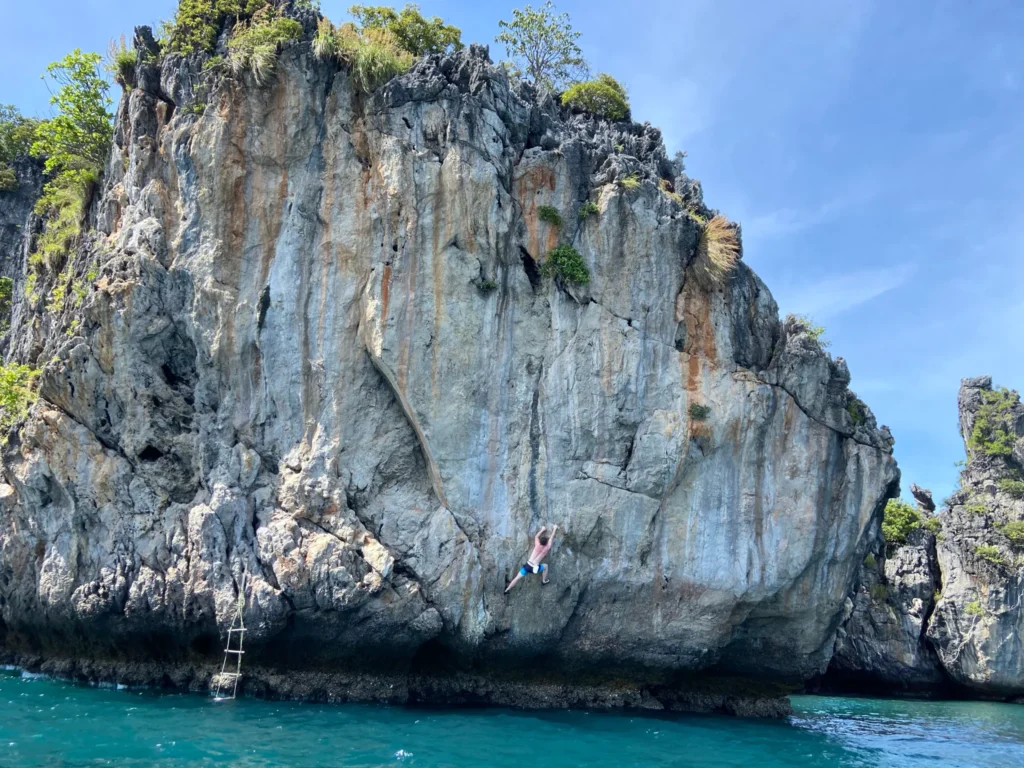 Grimpeur en Deep Water Solo sur une paroi calcaire au-dessus de l'eau turquoise, baie de Lan Ha, Vietnam