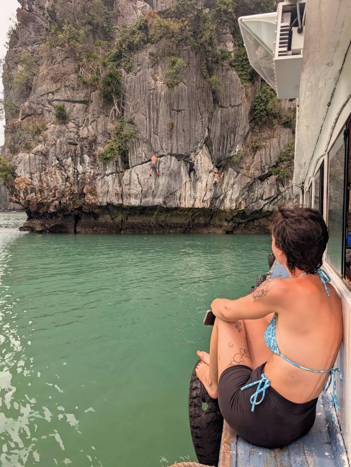 Des grimpeurs en Deep Water Solo sur la paroi, vus depuis le bateau, baie de Ha Long