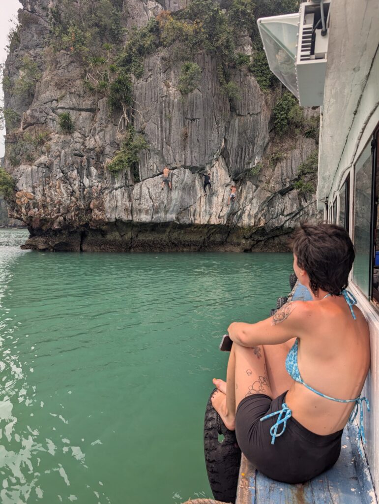 Des grimpeurs en Deep Water Solo sur la paroi, vus depuis le bateau, baie de Lan Ha